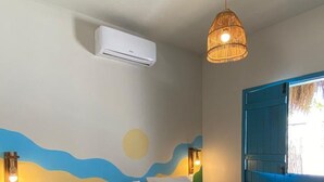 A bedroom with a bed, an air conditioner, a hanging light fixture, and a wall mural. - Pousada Vila Lua Bela (Pitimbu)