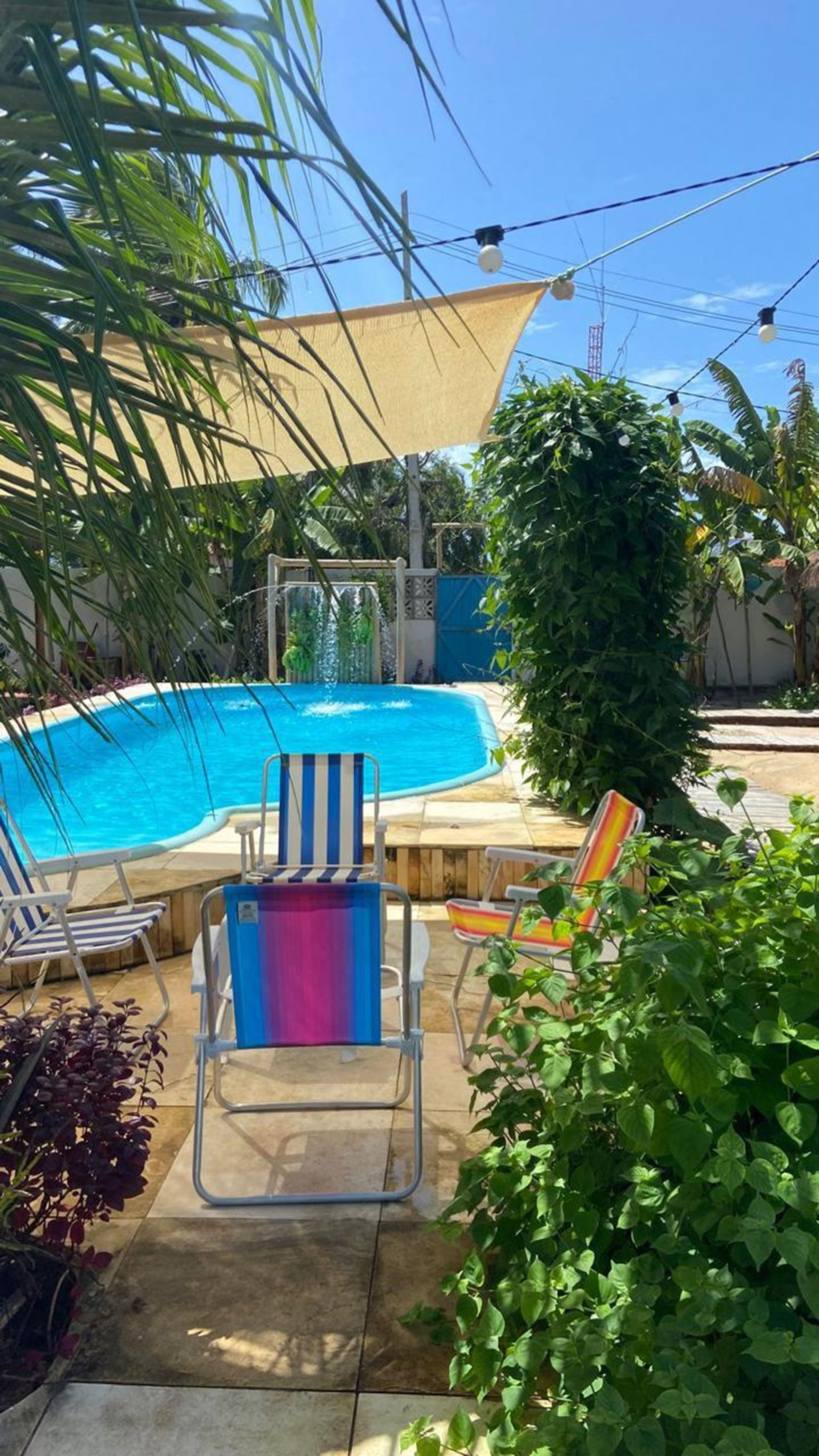 A swimming pool with lounge chairs, a shaded area, and surrounding greenery.