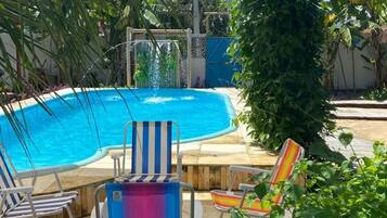 A swimming pool with lounge chairs, a shaded area, and surrounding greenery.