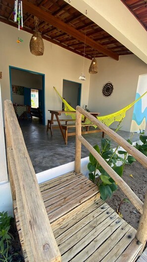 A wooden staircase leading to a covered area with a hammock, a table, and a hanging light fixture.