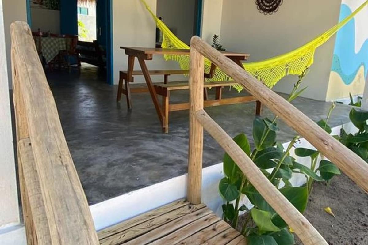 A wooden staircase leading to a covered outdoor area with a hammock and a dining table.