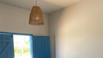 Quarto com duas camas, uma porta azul e luminária pendente.