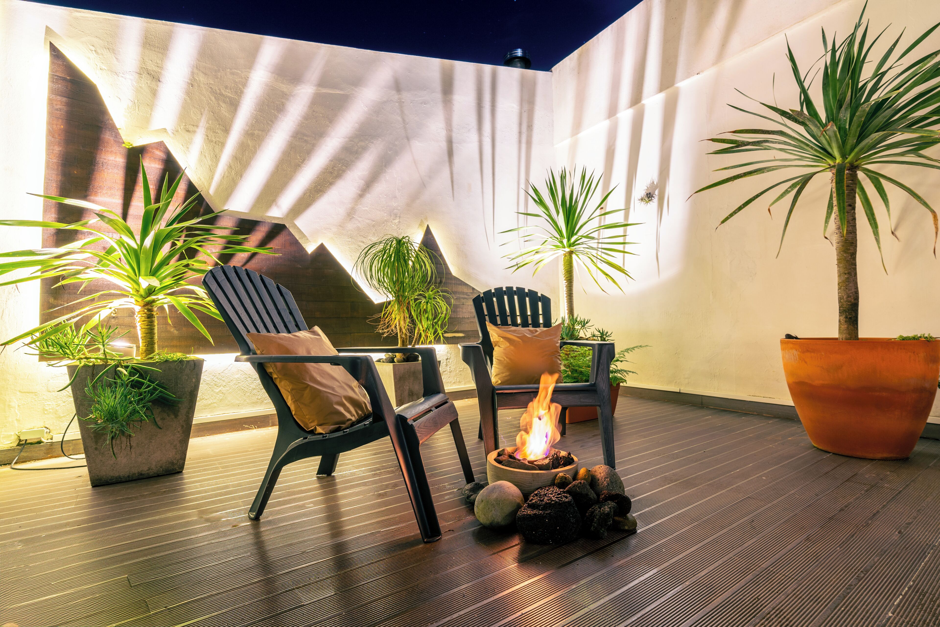 An outdoor seating area with chairs, a fire feature, and potted plants.