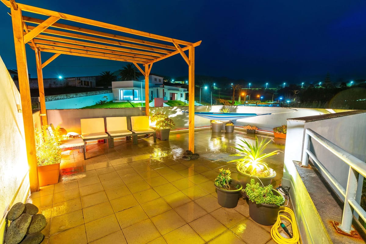 Una terraza en la azotea con una pérgola de madera, plantas en macetas y una piscina.