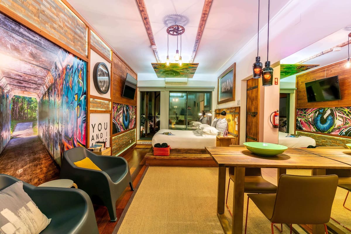 Un interior moderno con cama, zona de estar, mesa de comedor y obras de arte.