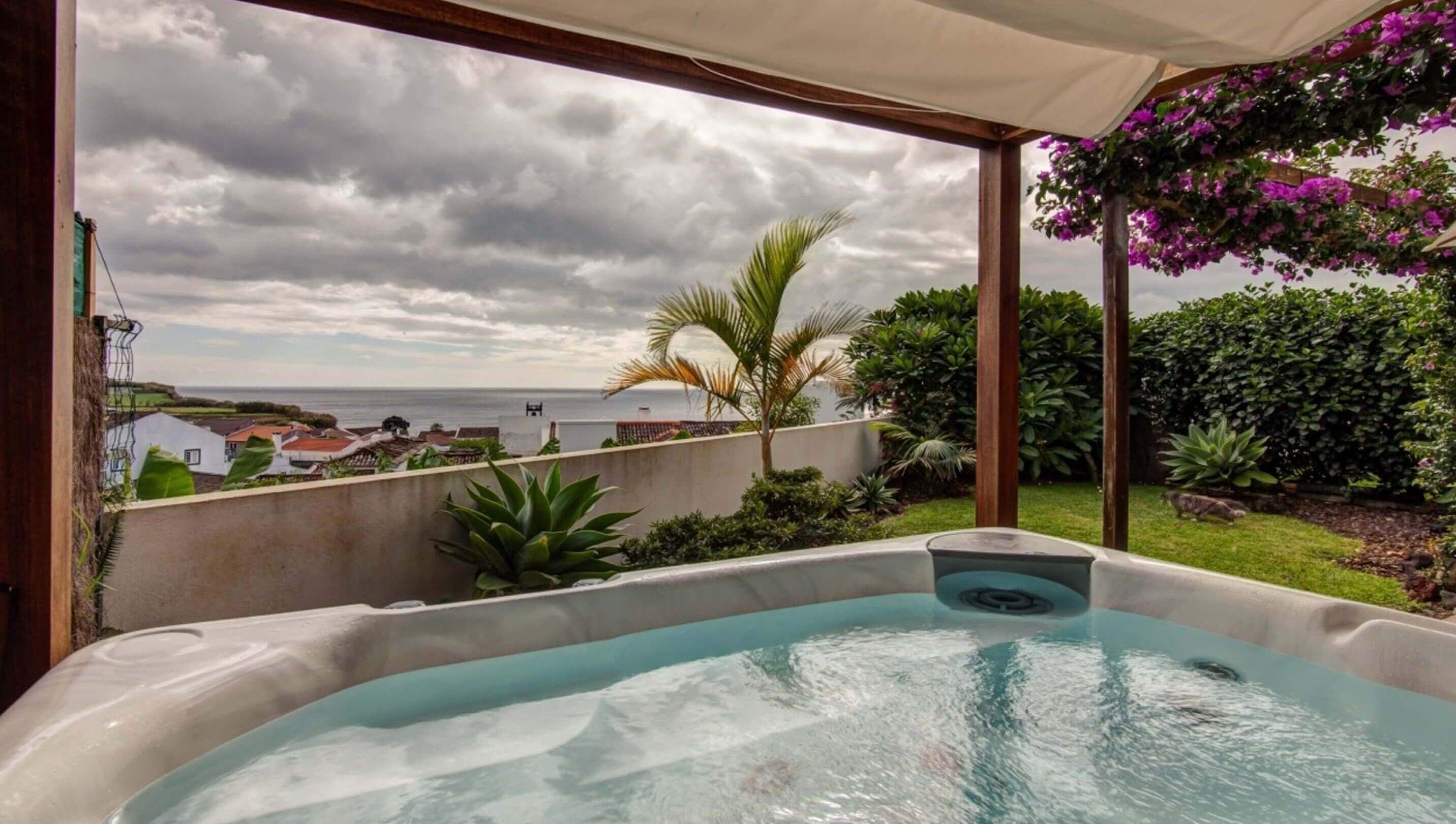 A hot tub with a view of the sea and a garden.