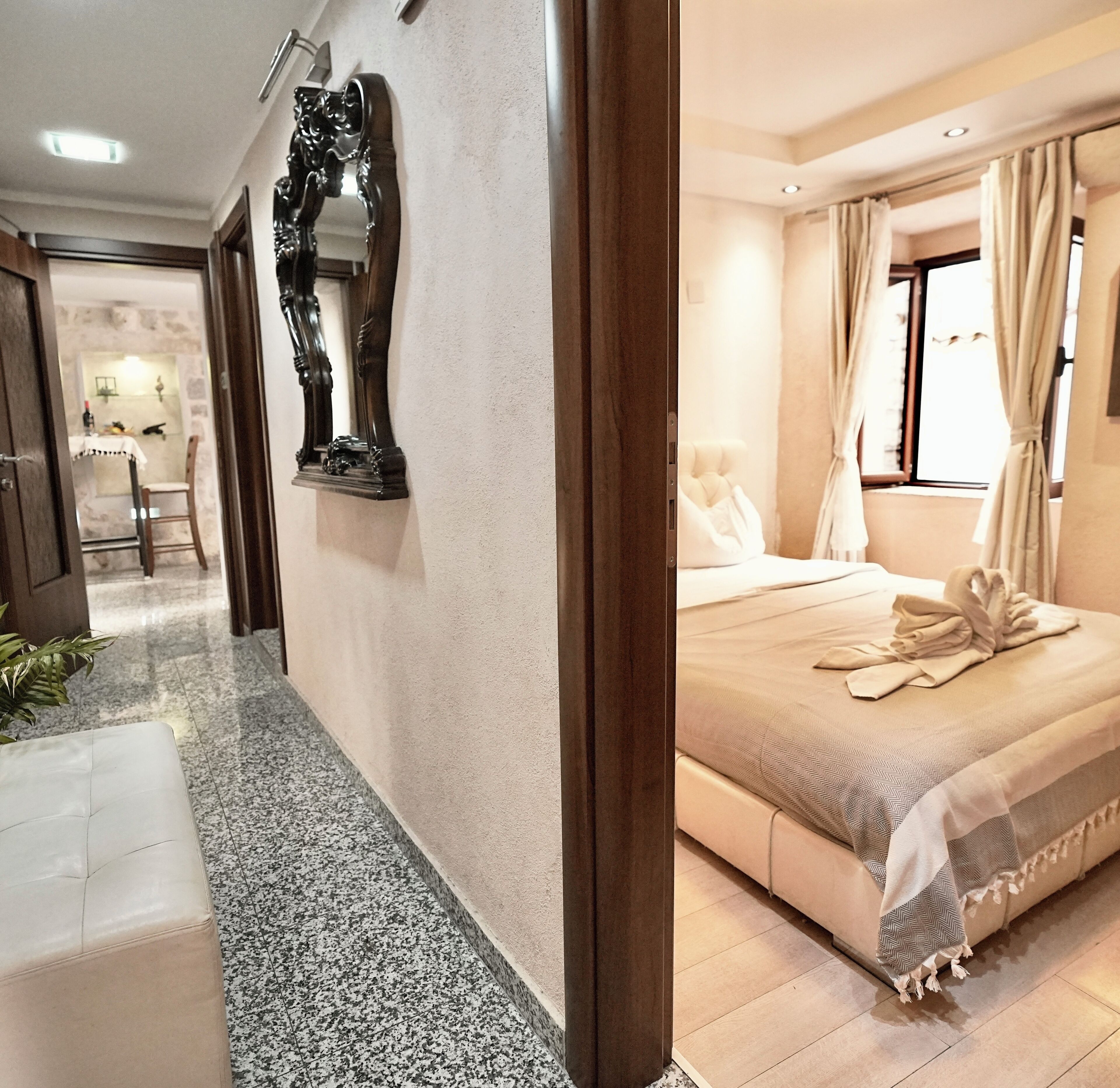 A hotel room with a bed, a mirror, a chair, and a small table.