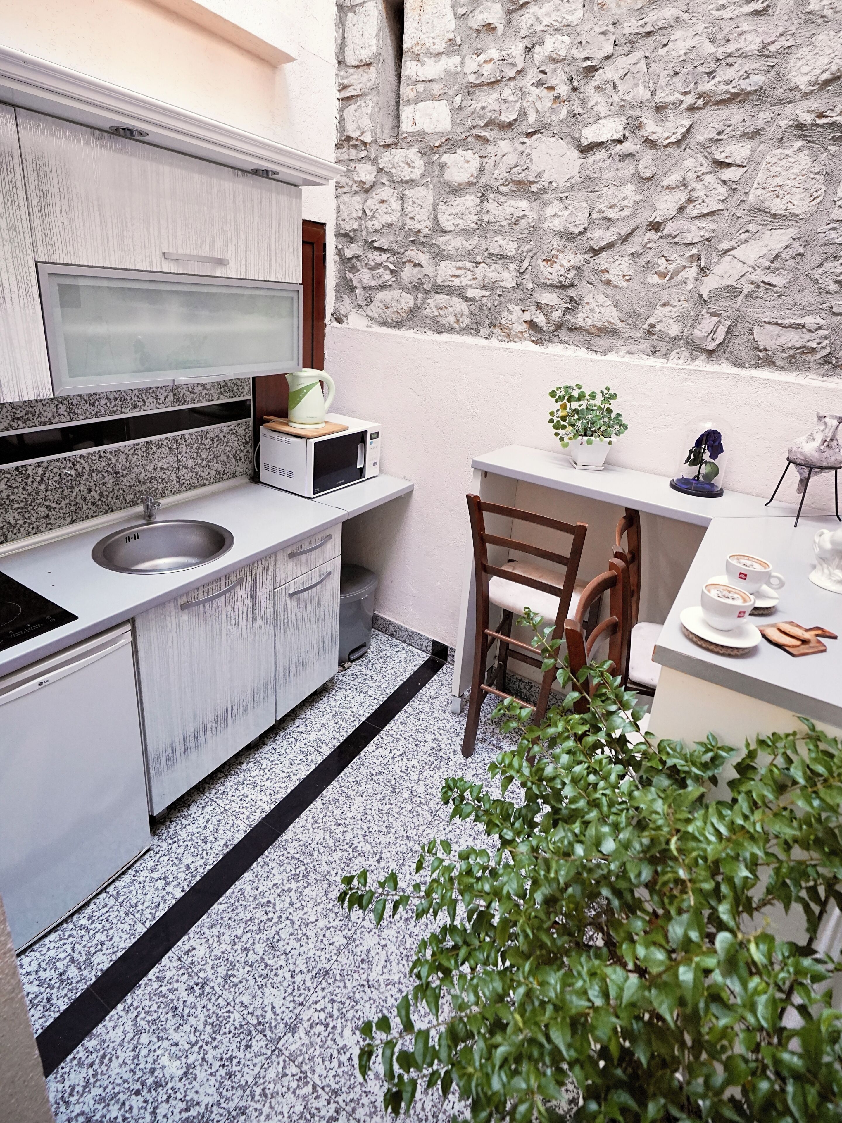 A compact kitchen with a sink, microwave, and a small dining table with chairs.