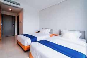 A hotel room with two beds, a door, and a wall-mounted air conditioning unit. - Angel Garden Resort (Busuanga)