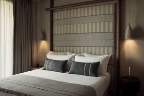 A neatly made bed with a striped headboard, two bedside lamps, and a bedside table with a candle. - Zelia Halkidiki (Nea Propontida)