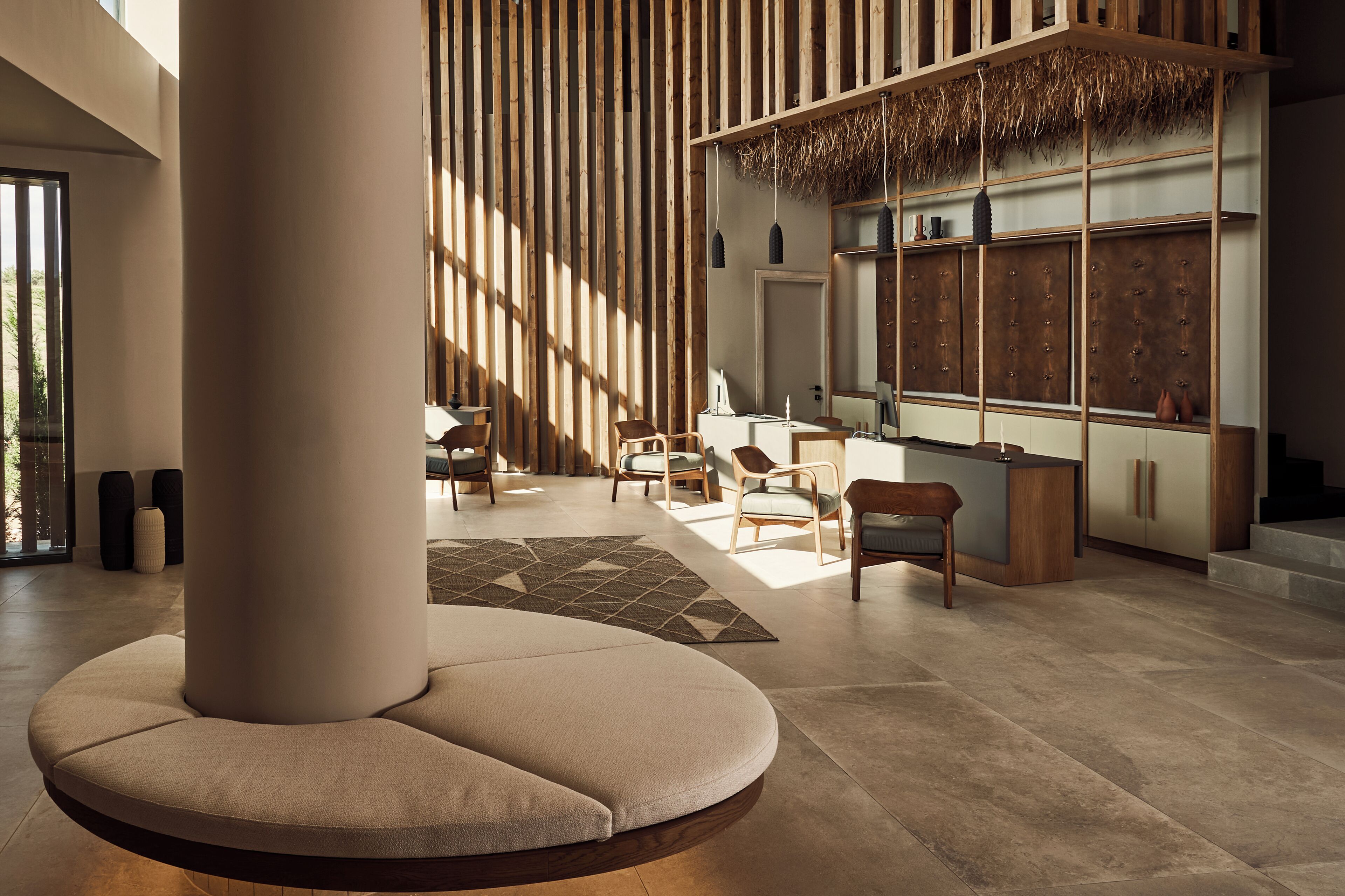 A modern interior with a central seating area, wooden slats, and a reception desk.