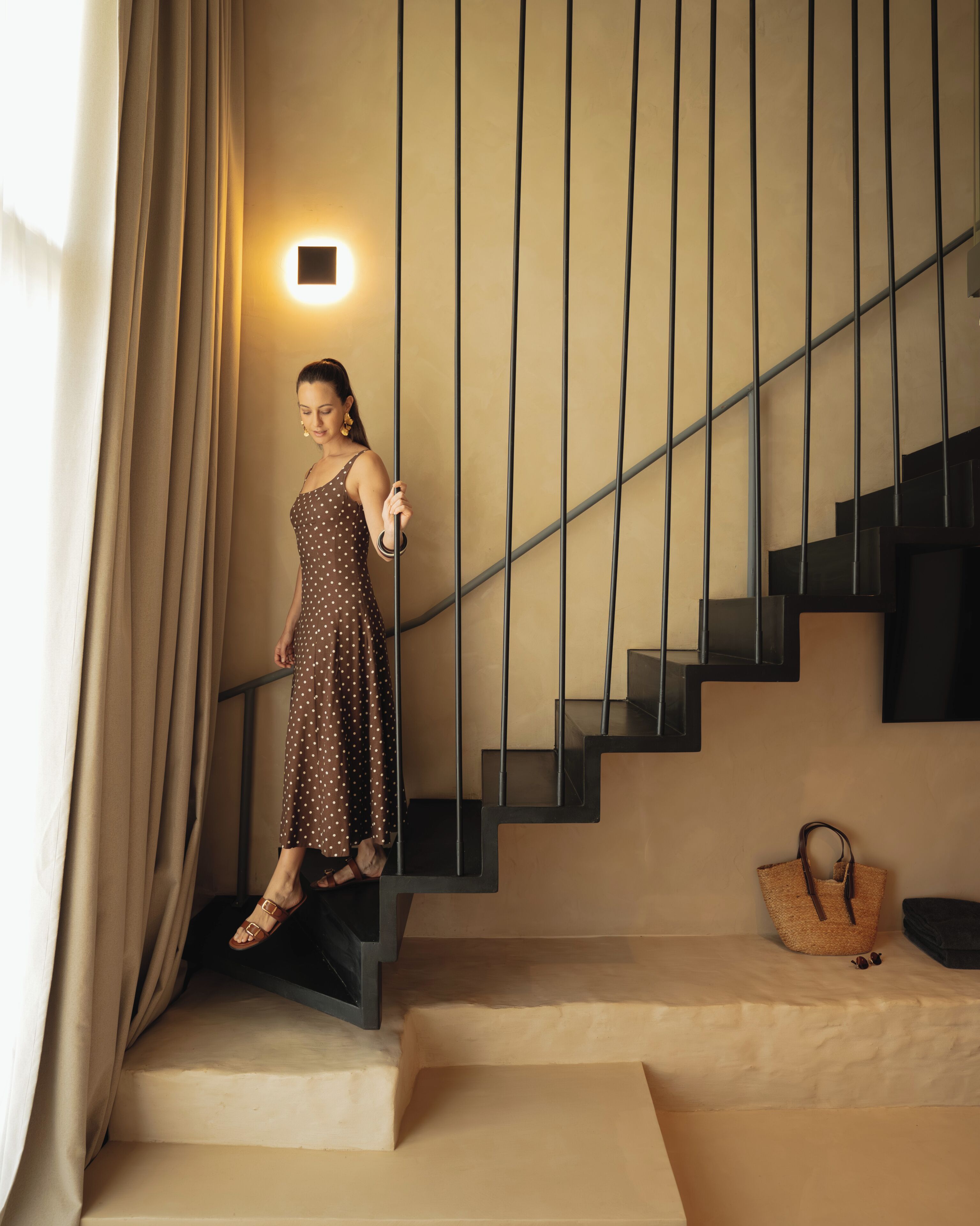 A woman descending a staircase with a light fixture above.