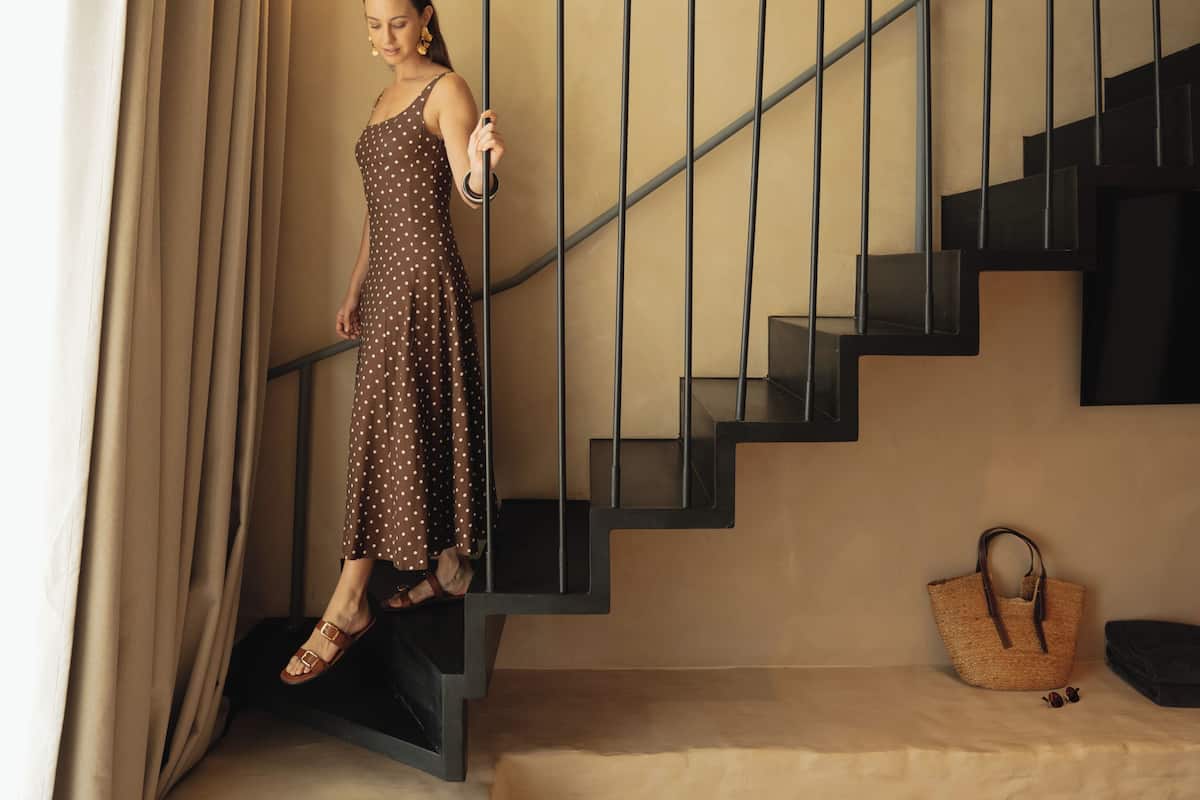 Una mujer bajando una escalera con un candelabro colgando.