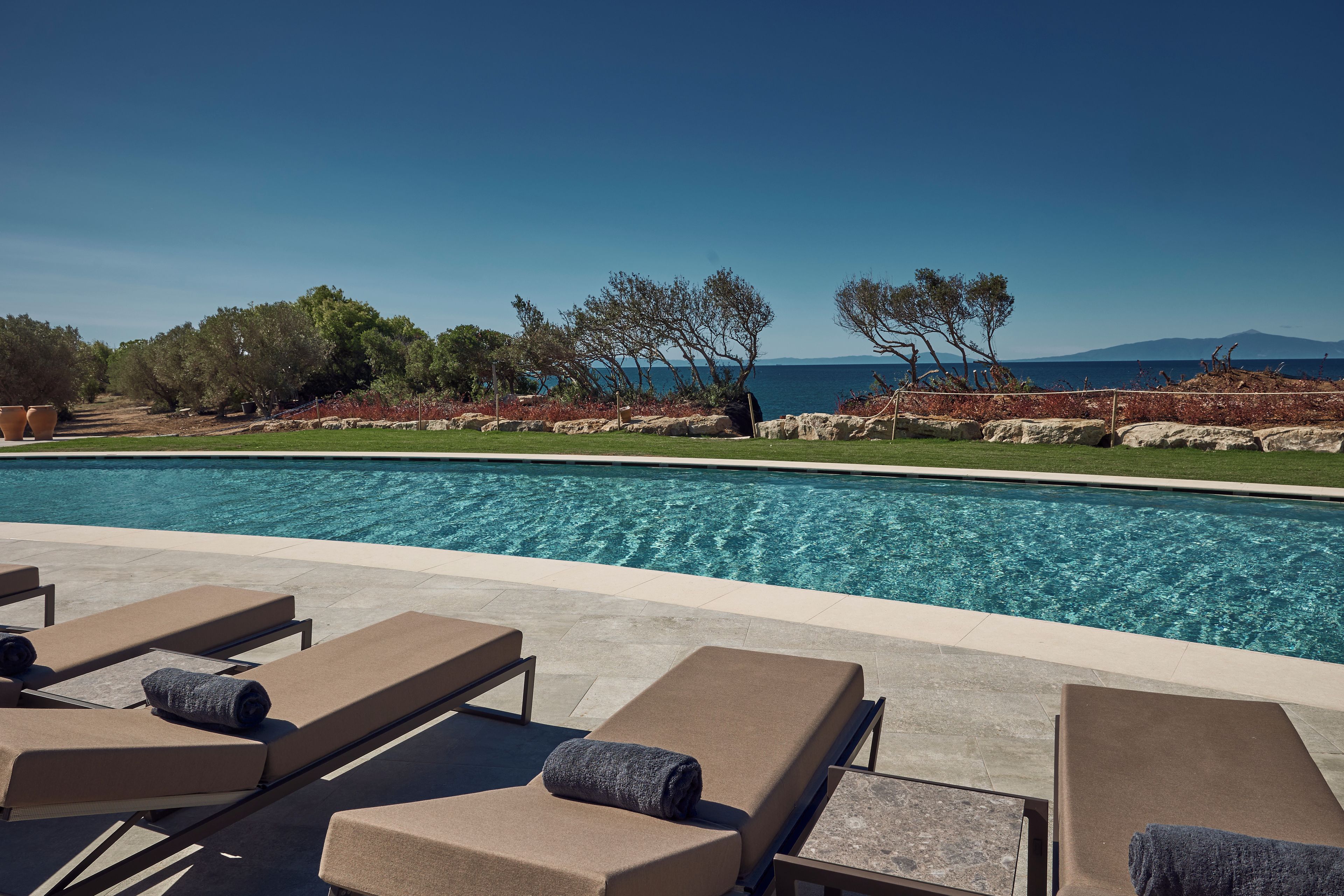 A poolside area with lounge chairs and a view of the sea.
