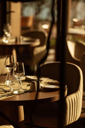 A dining table with wine glasses and salt and pepper shakers, set in a restaurant with wooden chairs. - Zelia Halkidiki (Nea Propontida)