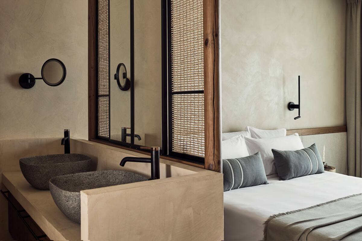 Un baño moderno con dos lavamanos de piedra, un espejo y un mueble de tocador de madera.