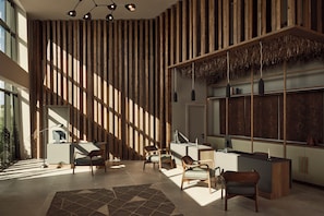 A modern interior with a reception desk, seating area, and large windows allowing natural light. - Zelia Halkidiki (Nea Propontida)