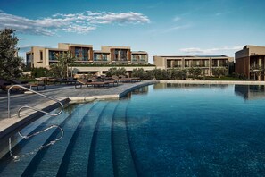 Un hôtel moderne doté d’une piscine, de chaises longues et offrant une vue sur un ciel dégagé.