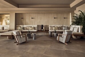 A spacious living area with sofas, armchairs, and coffee tables arranged around a central rug. - Zelia Halkidiki (Nea Propontida)