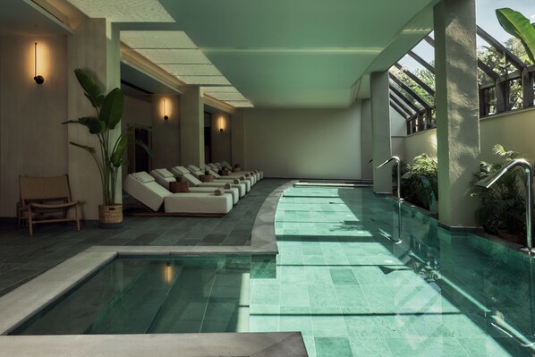 A pool area with lounge chairs, a wooden bench, and potted plants. - Zelia Halkidiki (Nea Propontida)