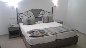 A bed with a headboard, two pillows, a blanket, and a bedside table with a lamp. - Hotel Diar Yassine Djerba (Aghir)