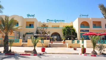 Un hotel amb entrada central, un rètol que diu 'Hotel Dior Massine' i un establiment proper anomenat 'Gelato Nativina'.