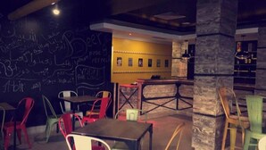 A restaurant interior with a chalkboard wall, tables, chairs, and a bar area. - Hotel Diar Yassine Djerba (Aghir)