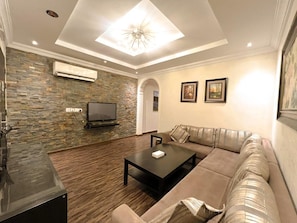 Una sala de estar moderna con una pared de piedra, un televisor de pantalla plana, un sofá seccional y una mesa de centro.