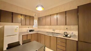 Una cocina con armarios de madera, un refrigerador blanco, un microondas, un lavamanos y una mesa.