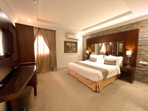 Habitación de hotel con una cama grande, un escritorio, una silla, un equipo de aire acondicionado y una pared decorativa de piedra.