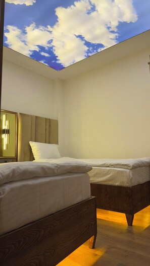 Ein Zimmer mit zwei Betten, einem Holzkopfstück, einem Spiegel und Blick zum Himmel durch die Decke.