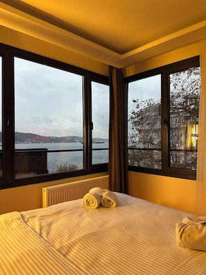 A hotel room with a bed, two windows, a view of a body of water, and a radiator. - Lokka Hotel Ortakoy (Istanbul)