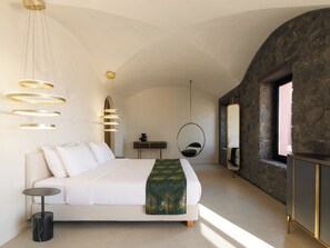 Ein modernes Schlafzimmer mit einem großen Bett, einem Hängekorbsessel, einem runden Spiegel und einer Steinwand.