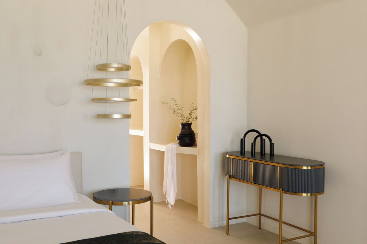 Ein modernes Hotelzimmer mit einem Bett, einem runden Tisch, einem Schminktisch mit Spiegel und einer Wanddekoration.