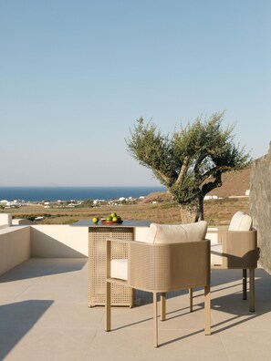 A terrace with wicker furniture and a view of the sea. - Elysian Retreat (Santorini)