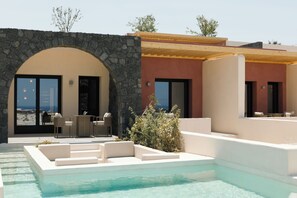A modern outdoor pool area with a stone archway, seating, and a view of the ocean.