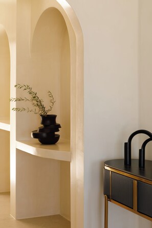 Ein modernes Interieur mit einer schwarzen Vase auf einem Regal, einem schwarzen Waschbecken und einem goldrahmenbesetzten Schrank.