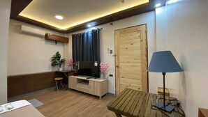 A room with a wooden desk, a television, a lamp, and a door. - Mom Shies Apartelle and Restaurant (Caba)