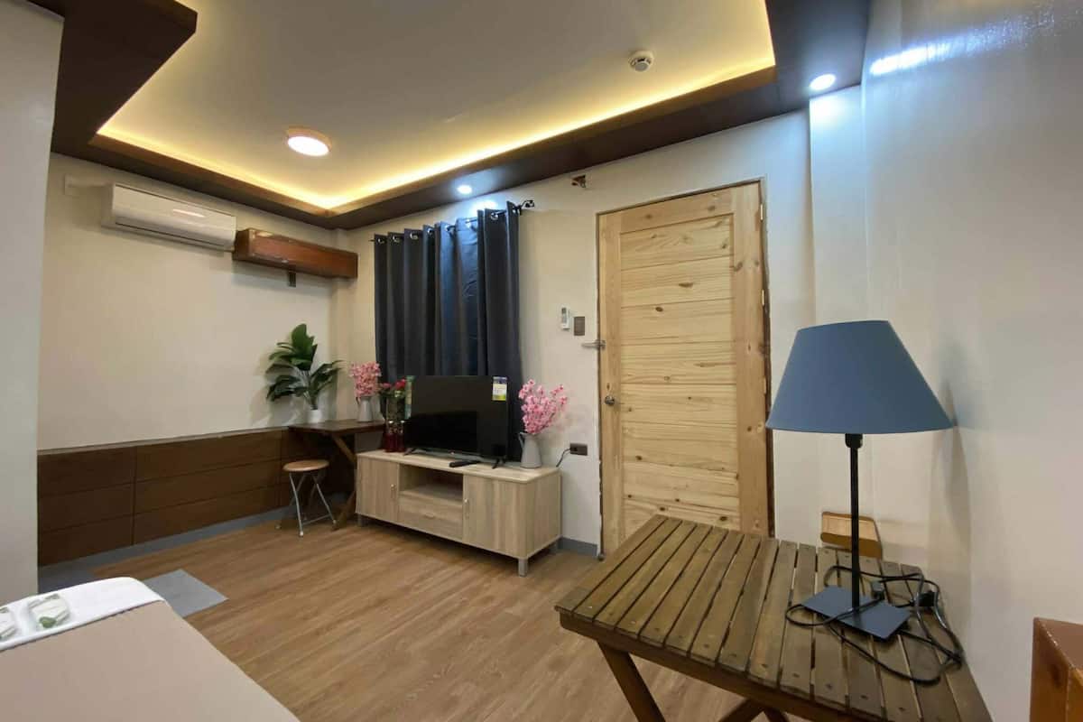 A room with a wooden desk, a television, a lamp, and a door.