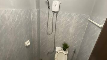 A bathroom with a toilet, shower, and sink.
