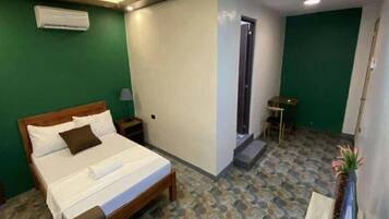 Ein Hotelzimmer mit Bett, Nachttisch, kleinem Tisch und Stuhl.