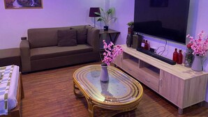 A living room with a sofa, TV, wooden cabinet, and a glass coffee table. - Mom Shies Apartelle and Restaurant (Caba)