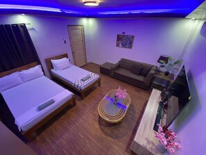 A hotel room with two beds, a sofa, a coffee table, a TV, and a door. - Mom Shies Apartelle and Restaurant (Caba)