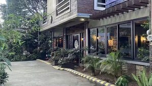 A building with a front entrance, large windows, and a small garden area with plants. - Mom Shies Apartelle and Restaurant (Caba)