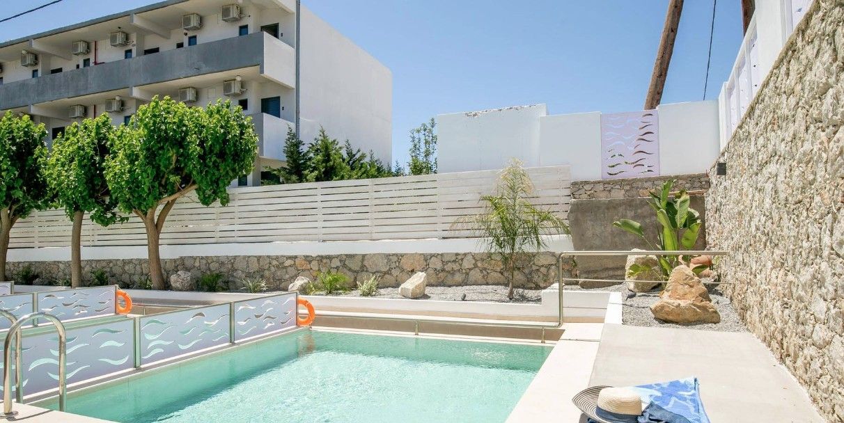 A swimming pool with a stone wall and a palm tree.