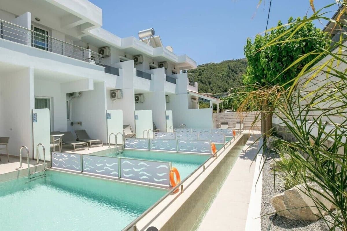 Un hôtel moderne doté d’une piscine sur le toit, d’un espace extérieur aménagé et offrant une vue sur les collines.