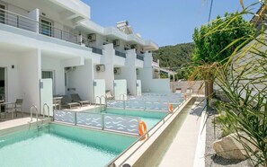 A modern hotel with a rooftop pool, outdoor seating, and a view of the hills. - Stay Helios (Rhodes)