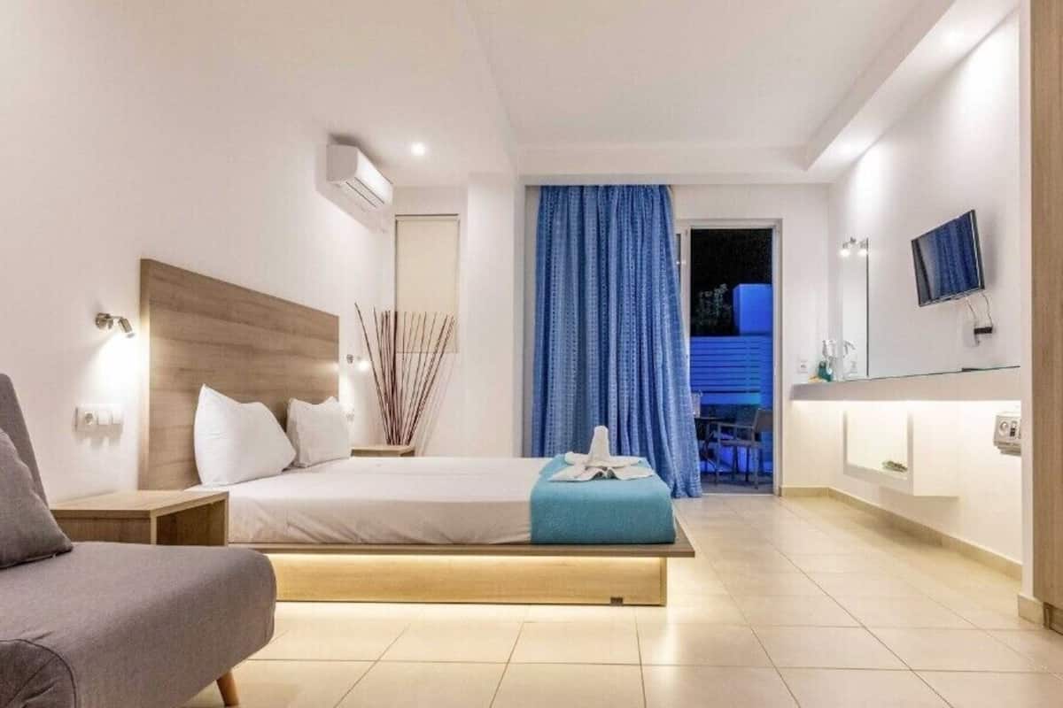 Une chambre d’hôtel moderne équipée d’un lit, d’une table de chevet, d’une chaise, d’un téléviseur et d’une salle de bain avec un miroir et un lavabo.