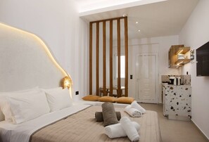 A modern hotel room with a bed, a wooden partition, a desk with a mirror, and a television on the wall.