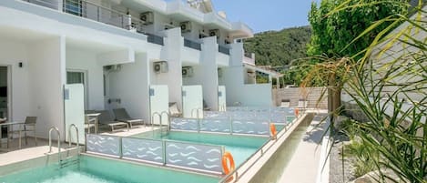 Un hotel moderno con piscina en la azotea, mobiliario exterior y vistas a las colinas.